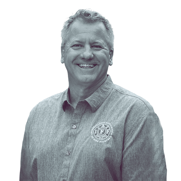 A black and white waist-up portrait of Brian Paquette, candidate for New Hampshire House District Hillsborough forty two, smiling and looking into the camera.